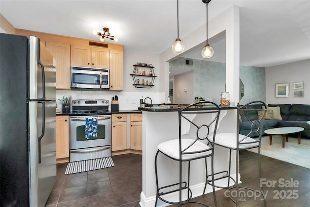 kitchen featuring stainless steel appliances, light brown cabinets, a kitchen bar, and kitchen peninsula