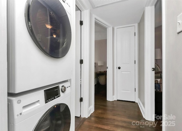 washroom with stacked washer and dryer and dark wood-type flooring