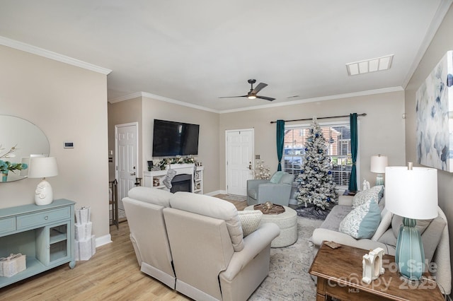 living room featuring ornamental molding, ceiling fan, and light wood-type flooring