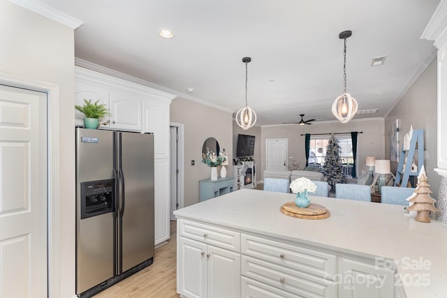 kitchen with white cabinetry, stainless steel refrigerator with ice dispenser, hanging light fixtures, and ornamental molding