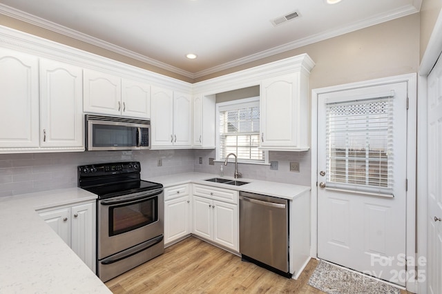 kitchen with white cabinetry, appliances with stainless steel finishes, sink, and light hardwood / wood-style floors