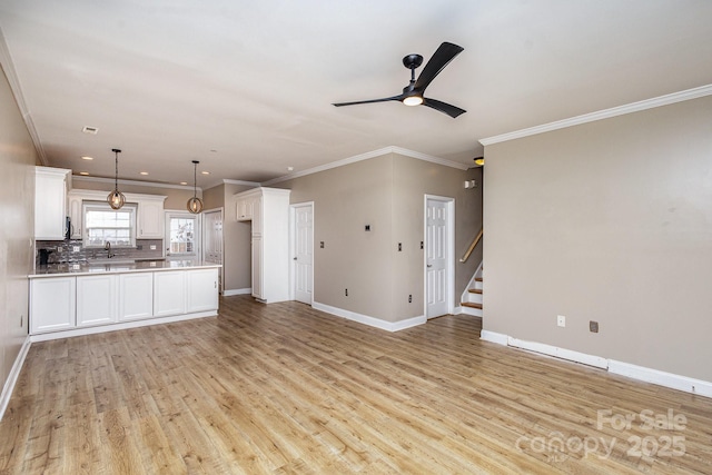 unfurnished living room with ceiling fan, ornamental molding, sink, and light wood-type flooring