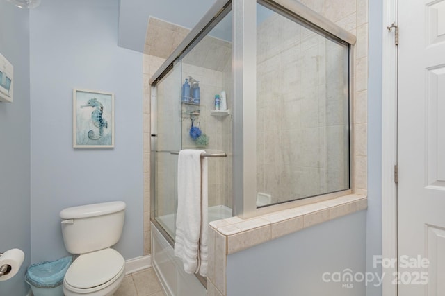 bathroom featuring bath / shower combo with glass door, tile patterned floors, and toilet