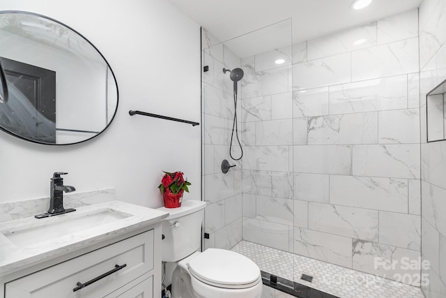 bathroom with vanity, toilet, and a tile shower