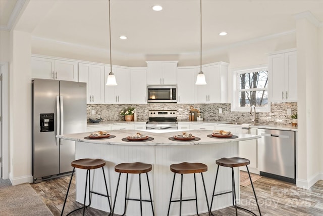 kitchen featuring a breakfast bar, a sink, backsplash, appliances with stainless steel finishes, and white cabinets