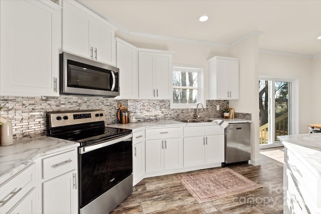 kitchen featuring a sink, appliances with stainless steel finishes, crown molding, and white cabinetry