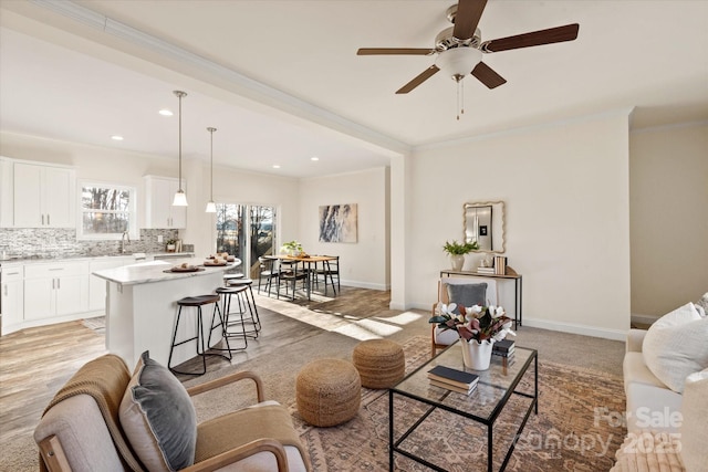 living room featuring a ceiling fan, recessed lighting, baseboards, and ornamental molding