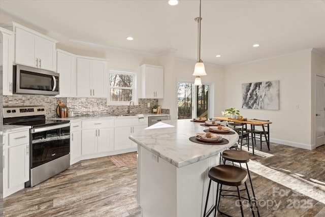 kitchen with decorative backsplash, a center island, light wood-type flooring, and stainless steel appliances