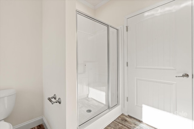 full bathroom featuring a shower stall, crown molding, baseboards, toilet, and wood finished floors