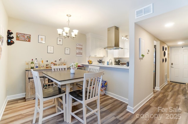 dining room featuring a chandelier, sink, and light hardwood / wood-style flooring