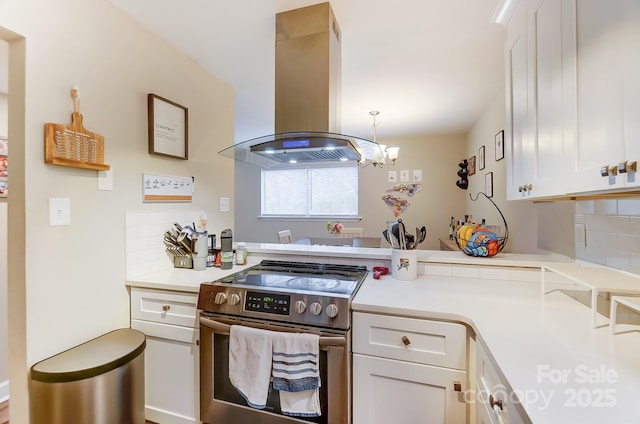 kitchen featuring a notable chandelier, island range hood, white cabinets, decorative backsplash, and stainless steel electric stove