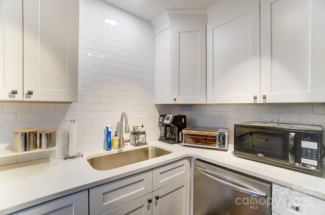 kitchen featuring backsplash, dishwasher, sink, and white cabinets