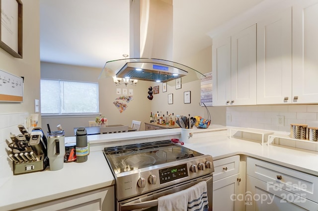 kitchen with island range hood, white cabinets, backsplash, and stainless steel range with electric stovetop