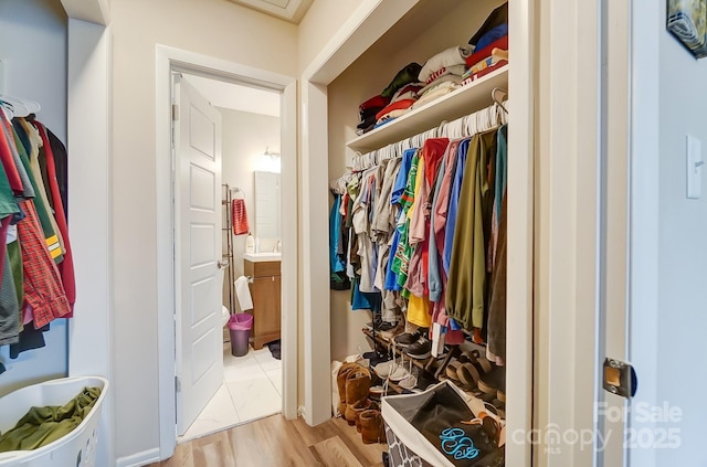 walk in closet with light hardwood / wood-style flooring