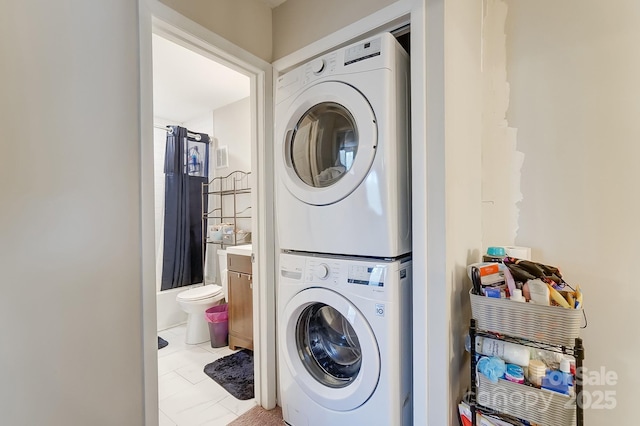 laundry area featuring light tile patterned flooring and stacked washer / drying machine