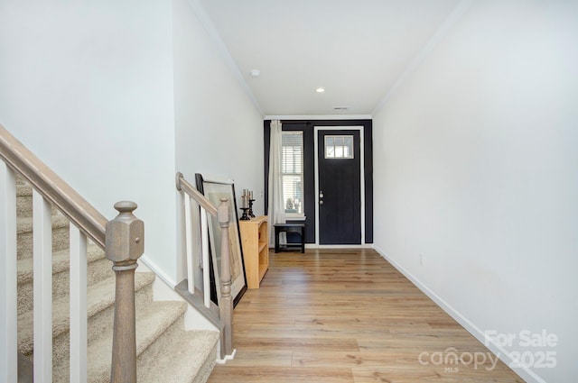 foyer entrance with ornamental molding and light hardwood / wood-style floors