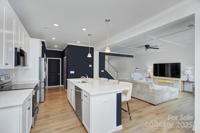 kitchen featuring appliances with stainless steel finishes, a breakfast bar, an island with sink, sink, and white cabinets