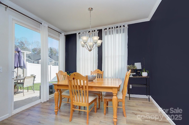 dining room featuring ornamental molding, light wood-type flooring, and a notable chandelier