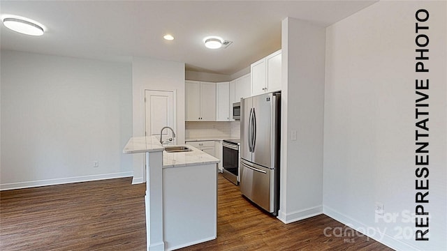 kitchen featuring sink, white cabinetry, light stone counters, a center island with sink, and appliances with stainless steel finishes