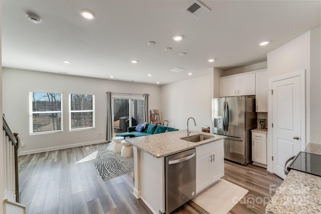 kitchen with appliances with stainless steel finishes, sink, a center island with sink, and white cabinets