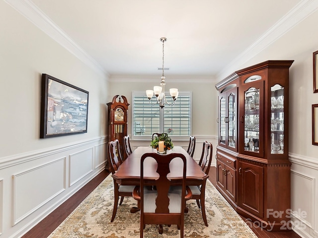 dining space featuring dark hardwood / wood-style flooring, ornamental molding, and a chandelier