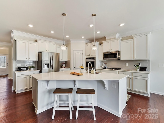 kitchen featuring a breakfast bar area, a center island with sink, appliances with stainless steel finishes, dark hardwood / wood-style flooring, and pendant lighting