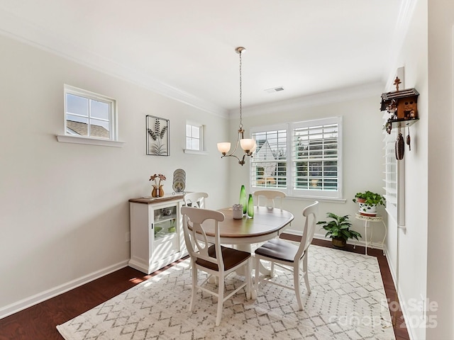 dining area featuring ornamental molding, dark wood-type flooring, and a notable chandelier