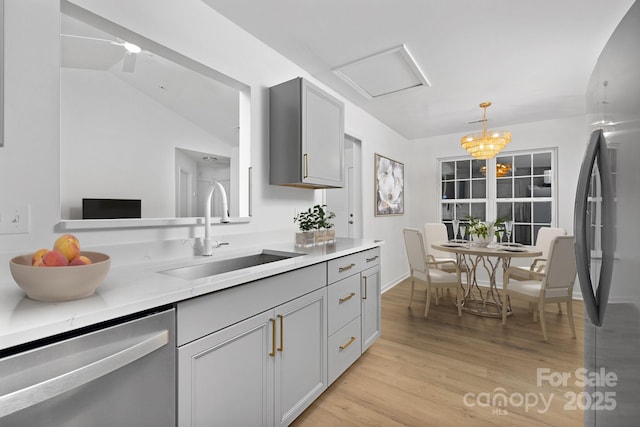 kitchen featuring sink, light hardwood / wood-style flooring, gray cabinets, pendant lighting, and stainless steel appliances