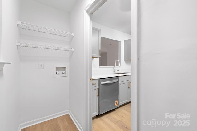 interior space featuring sink, hookup for a washing machine, and light hardwood / wood-style floors