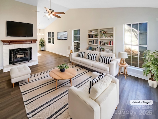 living room featuring lofted ceiling, a brick fireplace, dark wood-type flooring, and ceiling fan