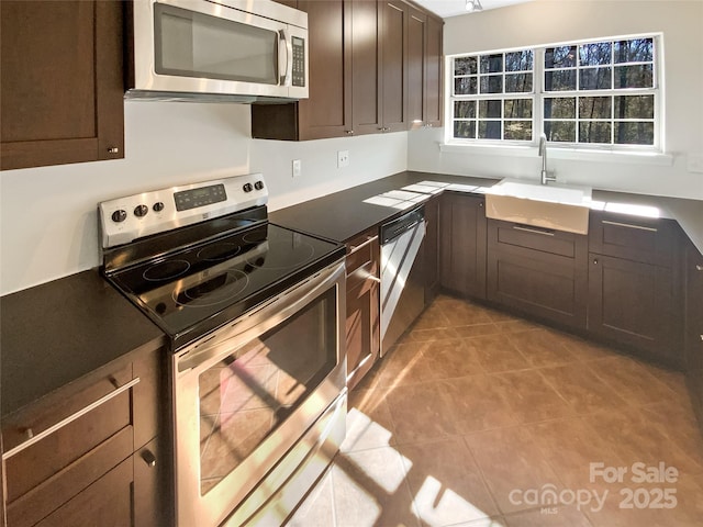 kitchen with sink, dark brown cabinets, stainless steel appliances, and light tile patterned flooring