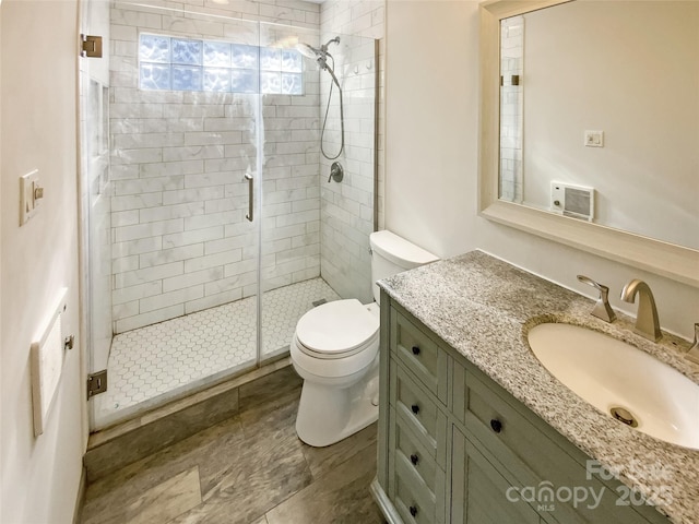 bathroom featuring vanity, a shower with shower door, and toilet