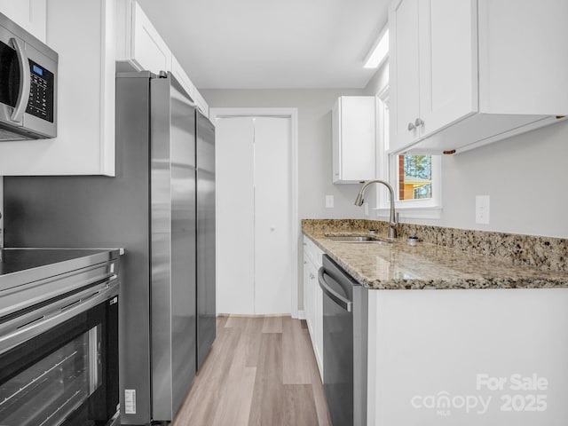 kitchen with white cabinetry, appliances with stainless steel finishes, sink, and light stone counters