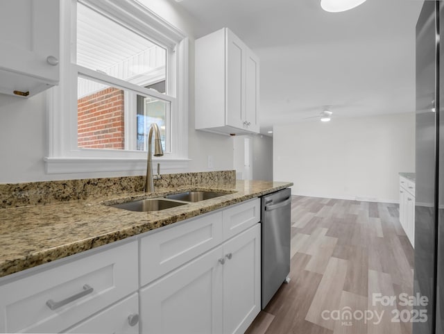 kitchen with sink, light stone countertops, white cabinets, and appliances with stainless steel finishes