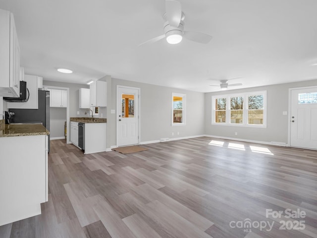 unfurnished living room featuring ceiling fan, sink, and light wood-type flooring