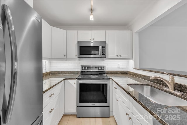 kitchen with sink, white cabinetry, tasteful backsplash, dark stone countertops, and appliances with stainless steel finishes