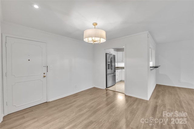 unfurnished dining area with ornamental molding and light wood-type flooring