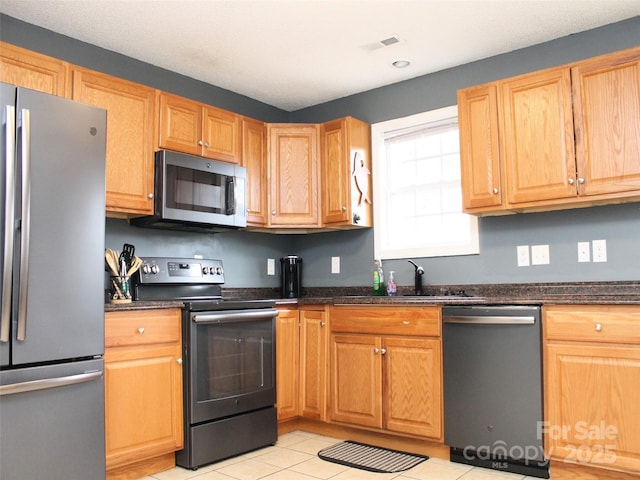 kitchen featuring appliances with stainless steel finishes, sink, and dark stone counters