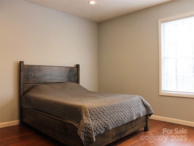 bedroom with multiple windows and dark wood-type flooring