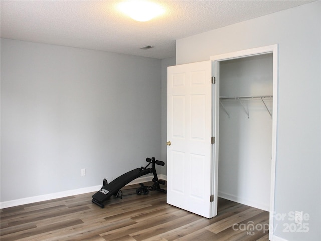 bedroom featuring dark wood-type flooring, a closet, and a textured ceiling