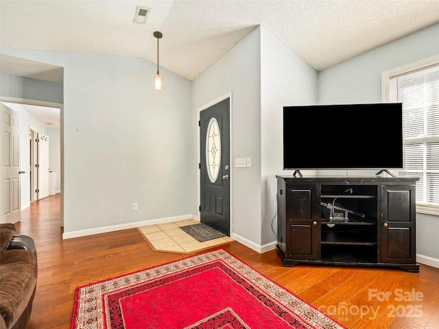 foyer with vaulted ceiling, wood-type flooring, and a textured ceiling