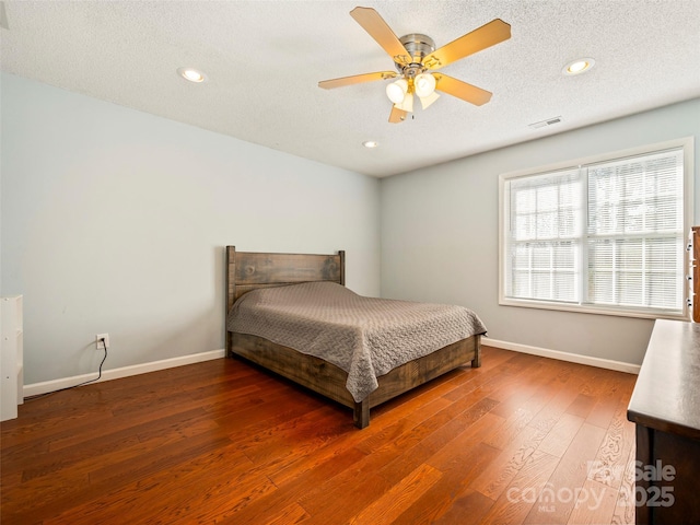 bedroom with dark wood-type flooring, ceiling fan, and a textured ceiling