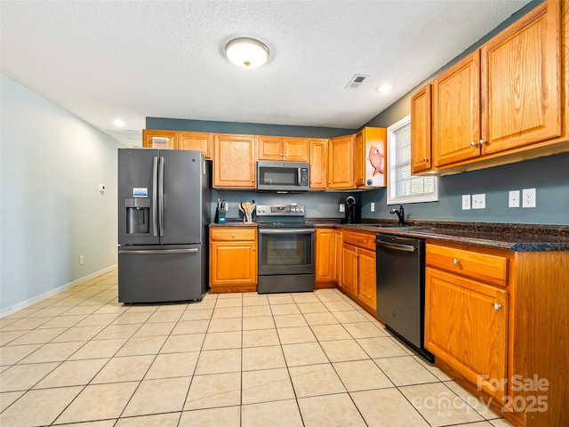 kitchen with light tile patterned floors, a textured ceiling, and black appliances