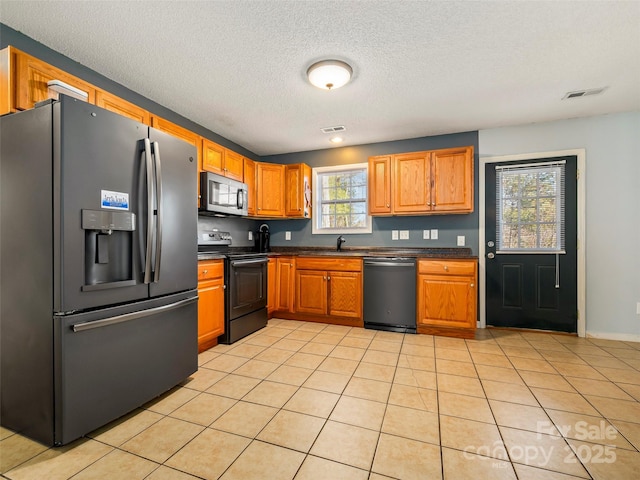 kitchen featuring stainless steel appliances, light tile patterned flooring, sink, and a textured ceiling