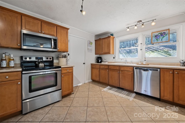 kitchen featuring stainless steel appliances, sink, light tile patterned floors, and a textured ceiling