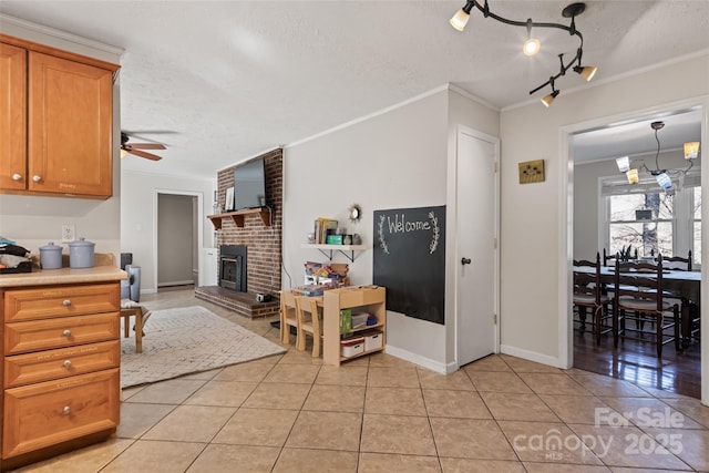 kitchen with pendant lighting, ceiling fan, ornamental molding, a textured ceiling, and light tile patterned flooring