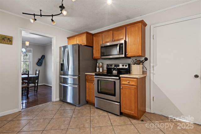 kitchen with light tile patterned floors, crown molding, a textured ceiling, and appliances with stainless steel finishes