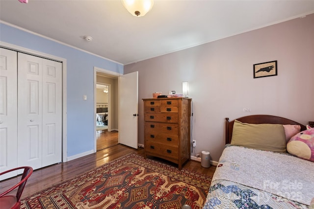 bedroom featuring crown molding, dark wood-type flooring, and a closet