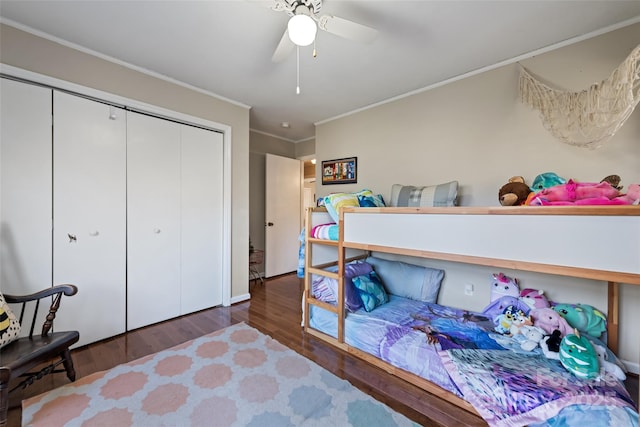 bedroom with ornamental molding, dark wood-type flooring, ceiling fan, and a closet