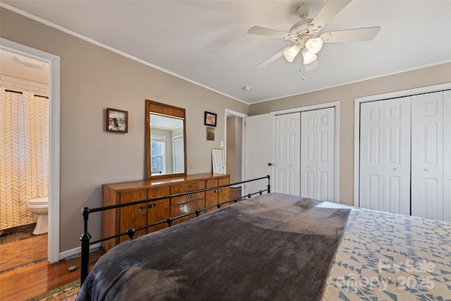 bedroom with ensuite bathroom, wood-type flooring, ceiling fan, multiple closets, and crown molding